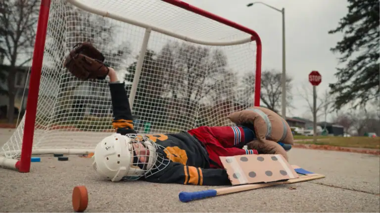 Child practicing hockey goalie save outside with hockey equipment.